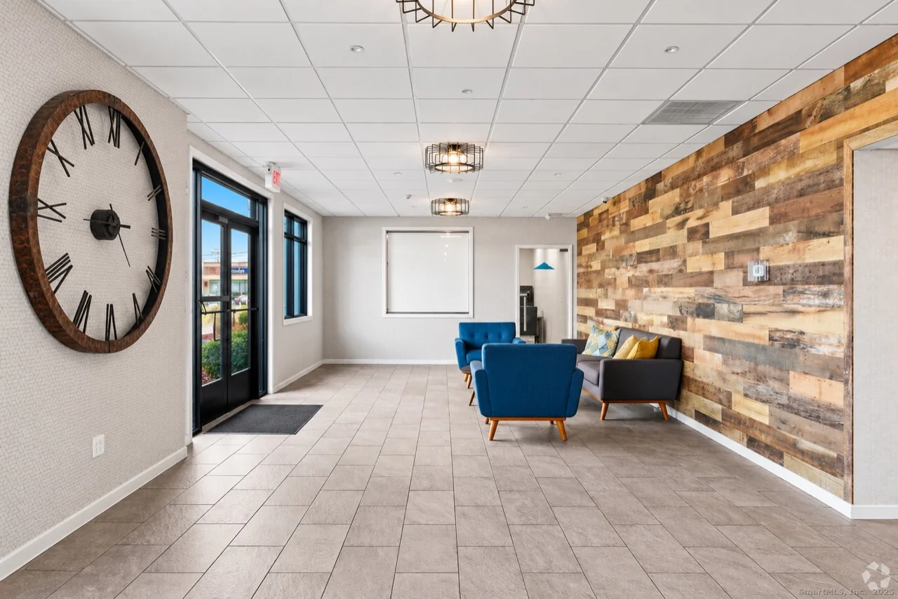 Empire 225 lobby lounge with blue armchairs and a wood accent wall
